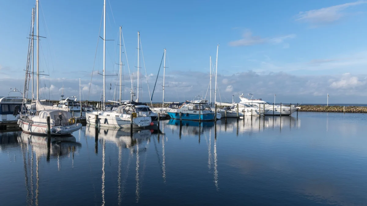 Vredige jachthaven weerspiegeld in kalm water onder een blauwe lucht in Årøsund, Denemarken.