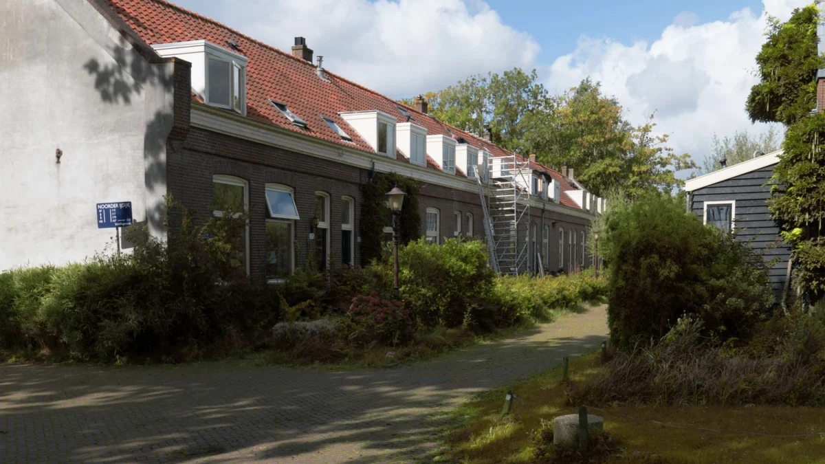 Een rij traditionele huizen in een rustige Amsterdamse buurt, waar het zonlicht goed verdeeld is.
