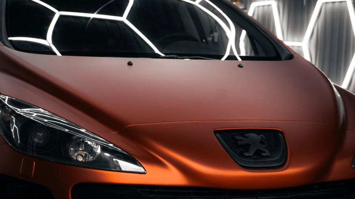 Een moderne oranje auto met een strak design, gefotografeerd in een goed verlichte garage.
