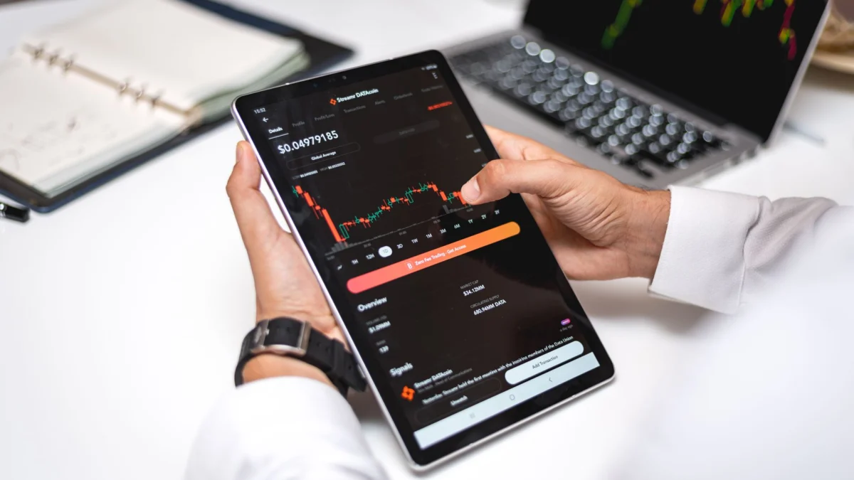 Professional analyseert cryptocurrency marktgegevens op een digitaal tablet met financiële grafieken.