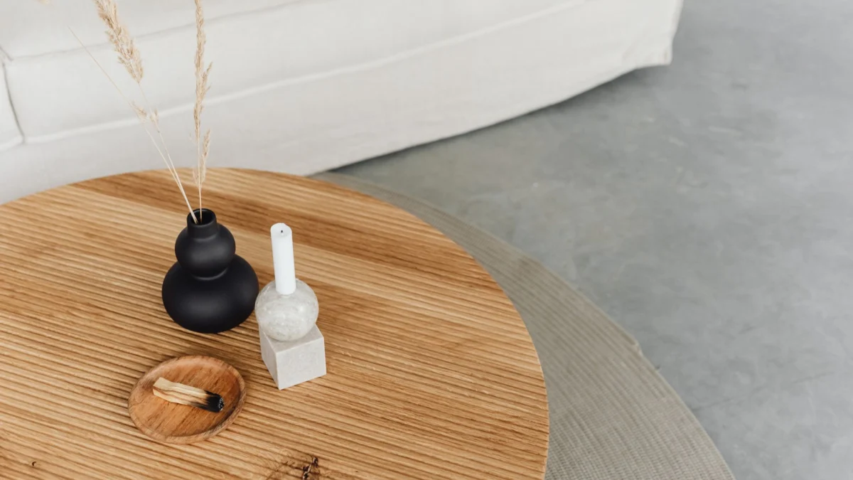 Stylische houten tafelopstelling met decoratieve vaas en kaars voor moderne woningdecoratie.