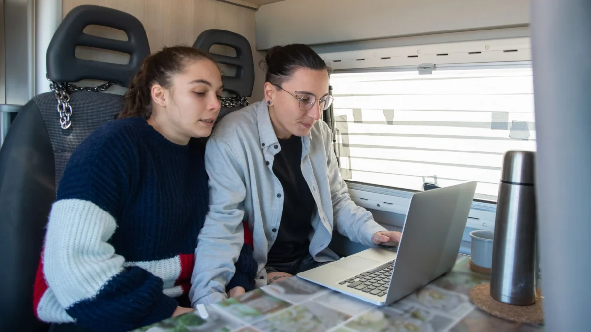 Een paar dat in een camper zit met een laptop, geniet van een gezellige tijd samen.