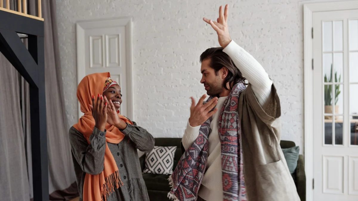 Een gelukkig multicultureel stel danst en viert samen binnenshuis.