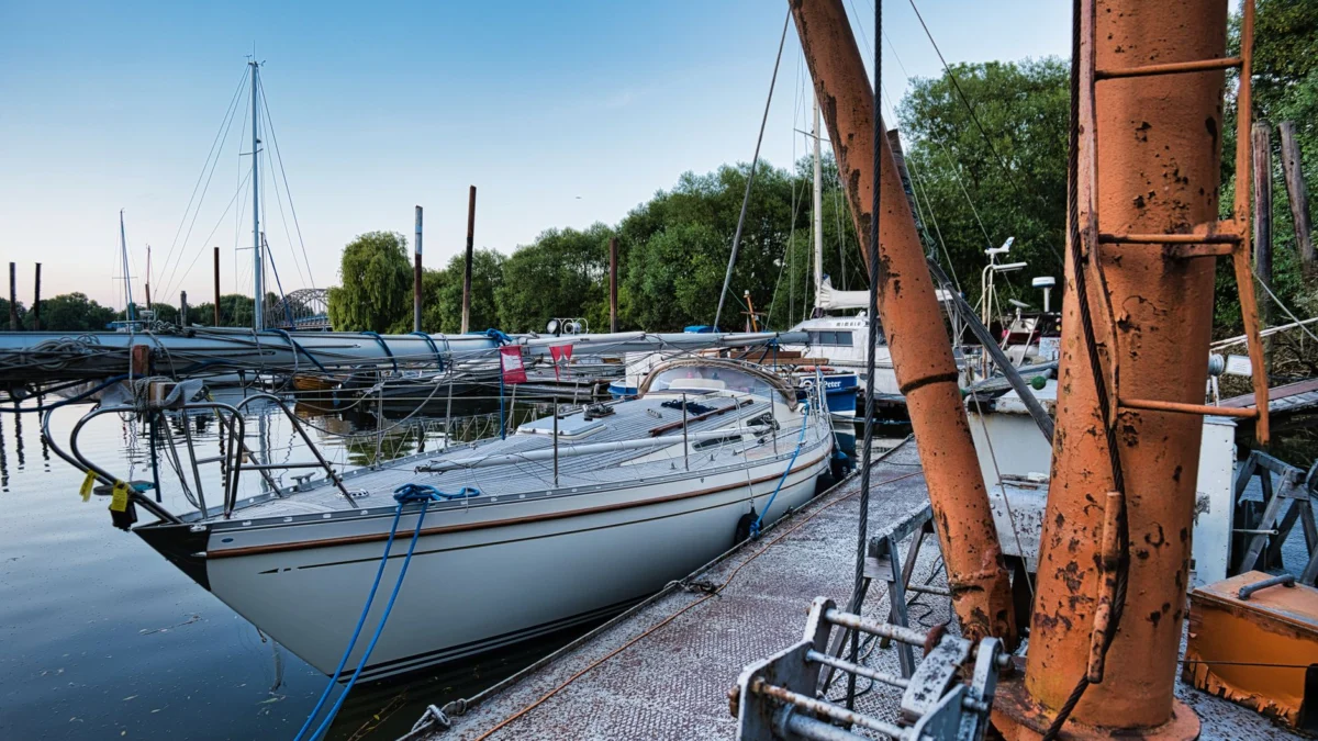 Rustig tafereel in de jachthaven met zeilboten die overdag aangemeerd liggen aan een rustieke steiger.