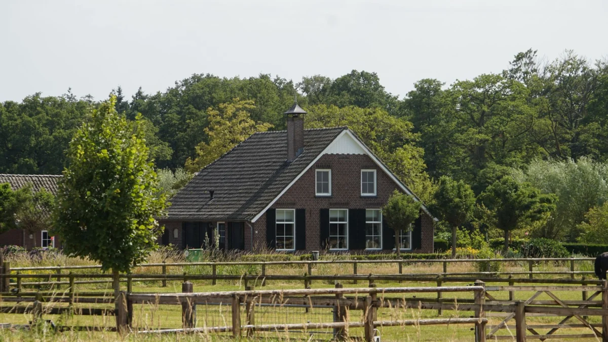 Klein pittoresk huis omgeven door weelderige groene natuur en houten hekken.