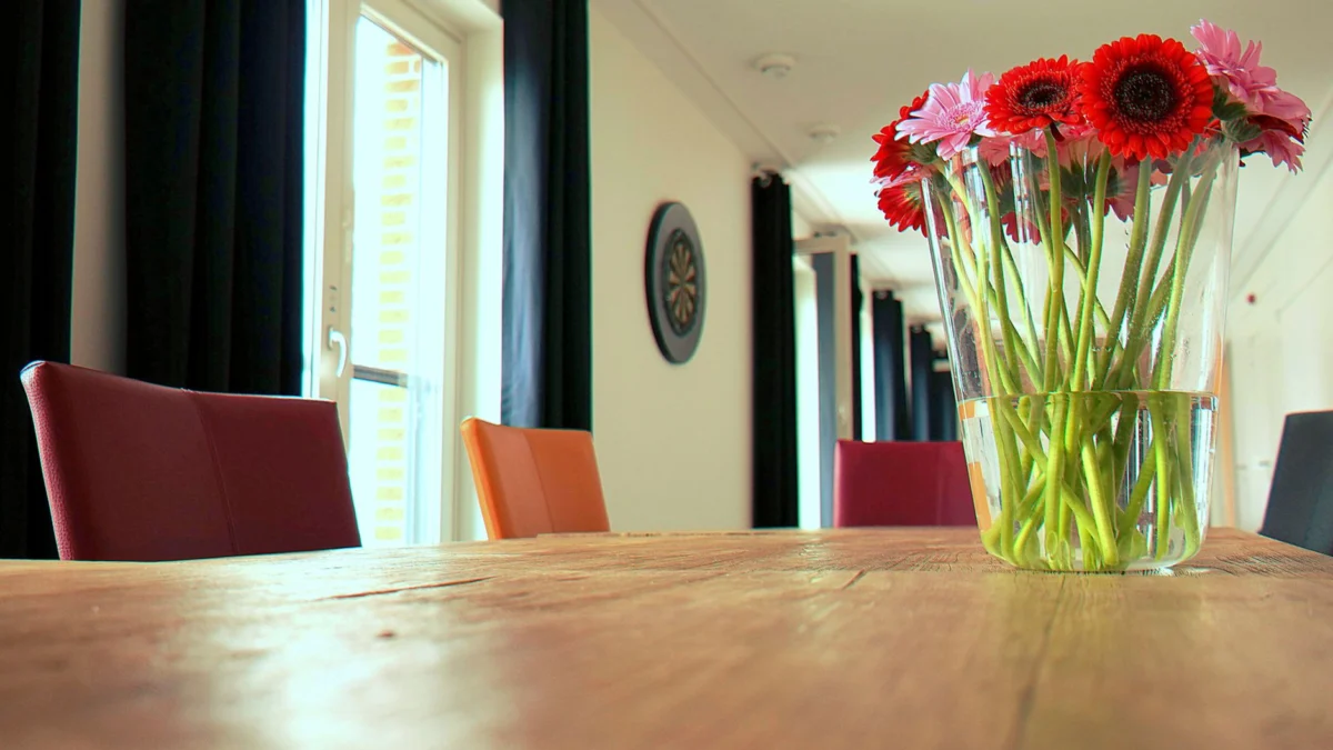 Een moderne eetkamerinterieur met levendige bloemen in een vaas op een houten tafel.