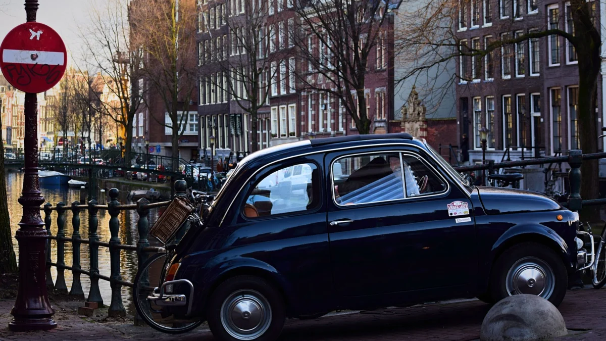 Classic vintage auto geparkeerd naast een kanaal in Amsterdam met een prachtig stadsarchitectuur.