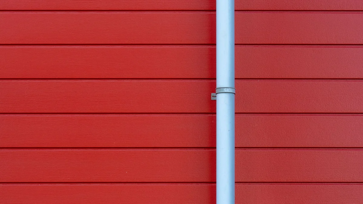 Een minimalistische foto van een rode muur met een witte regengoot, die schone lijnen en een levendig kleurcontrast toont.