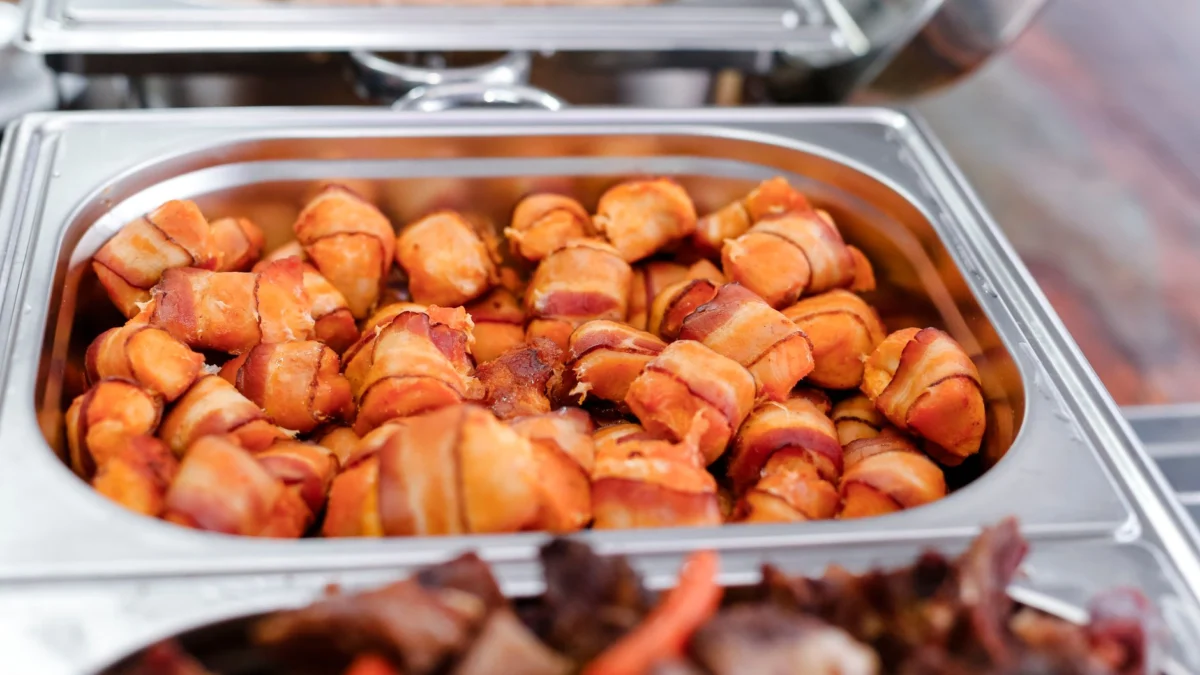 Heerlijke met bacon omhulde hapjes, klaar om te serveren in een cateringdienblad. Perfect voor evenementen.