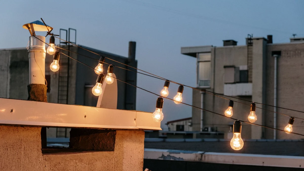 Warme sfeerverlichting op een dak creëert een gezellige atmosfeer tijdens de schemering in een stedelijke omgeving.