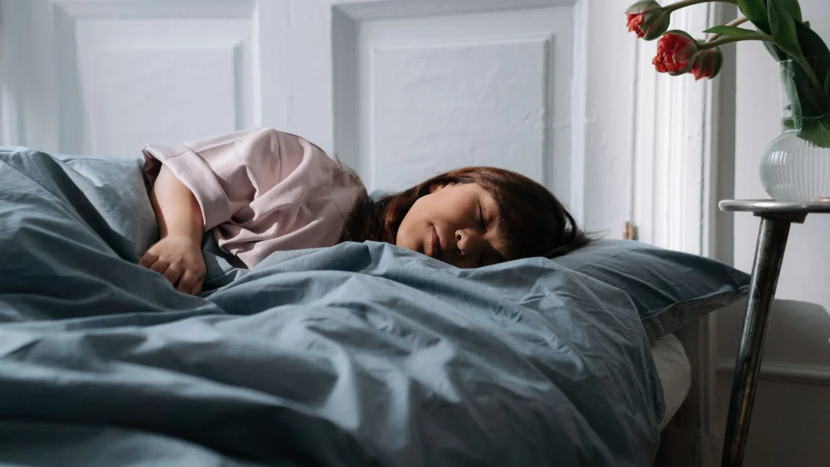 Aziatische vrouw die vredig slaapt in een gezellige slaapkamer, met een uitstraling van ochtendrust en ontspanning.