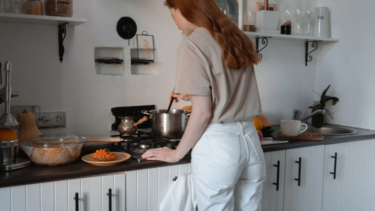 Vrouw kookt aan het fornuis in een gezellige moderne keuken omgeving.