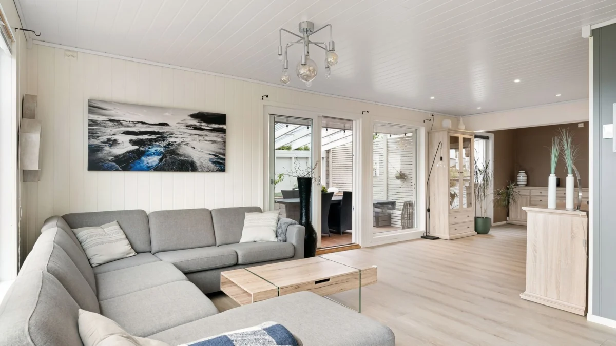 Heldere en luchtige woonkamer met een grijze bank en minimalistische decoratie, perfect voor verhuur.