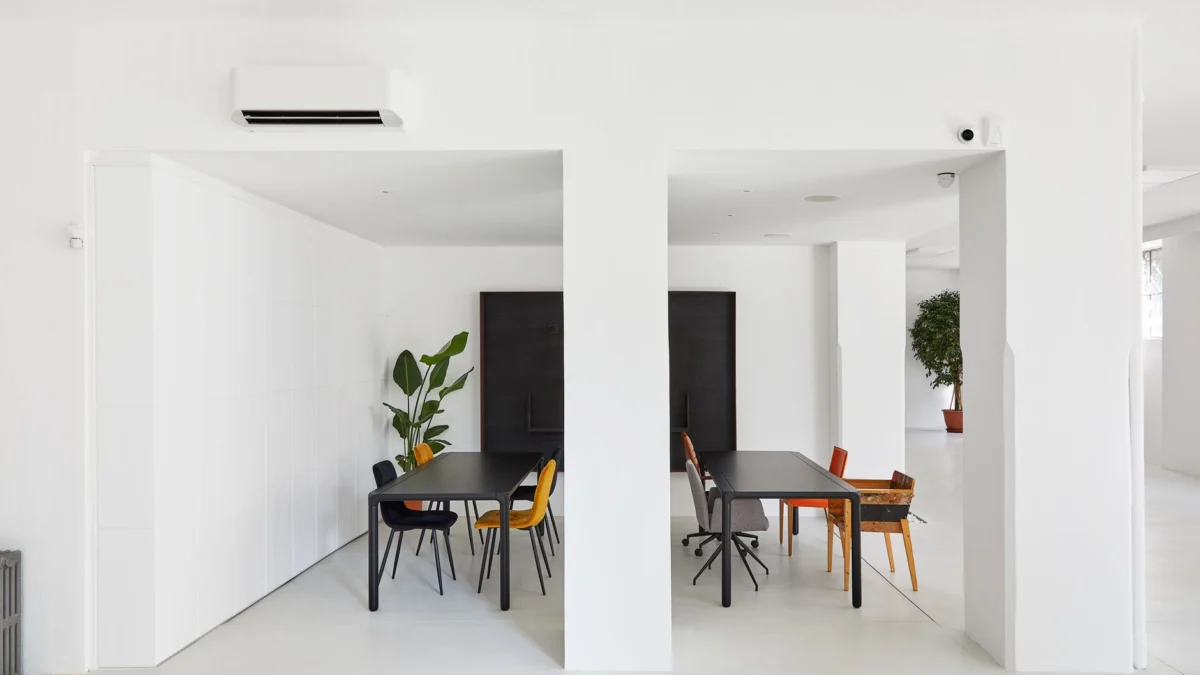 Heldere minimalistische kantoorruimte met strakke tafels en stoelen, inclusief natuurlijke planten.