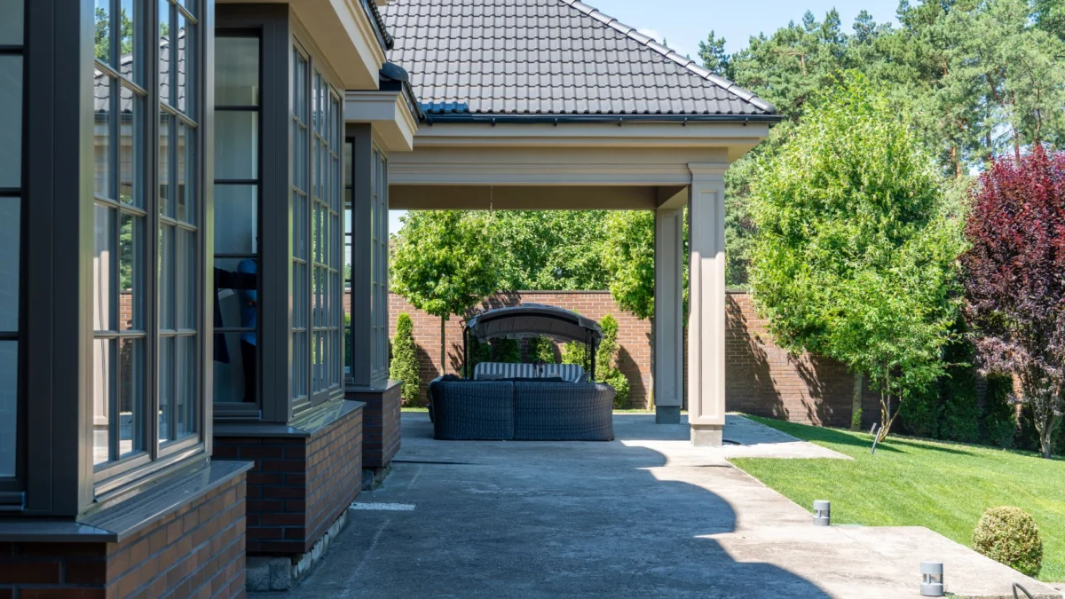 Ontspannende patio met moderne meubels, tuinview en tegelroof in een zomerse setting.