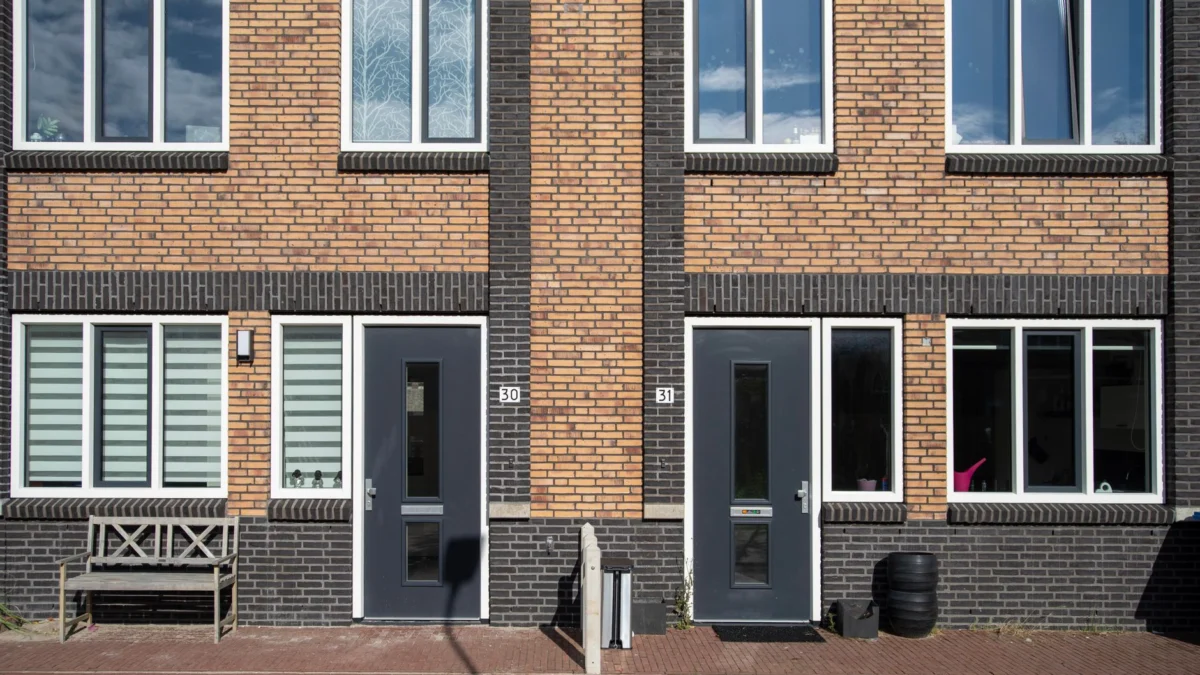 Een moderne gevel van baksteen met grote ramen en contrasterende deuren, een toonbeeld van hedendaagse architectuur.