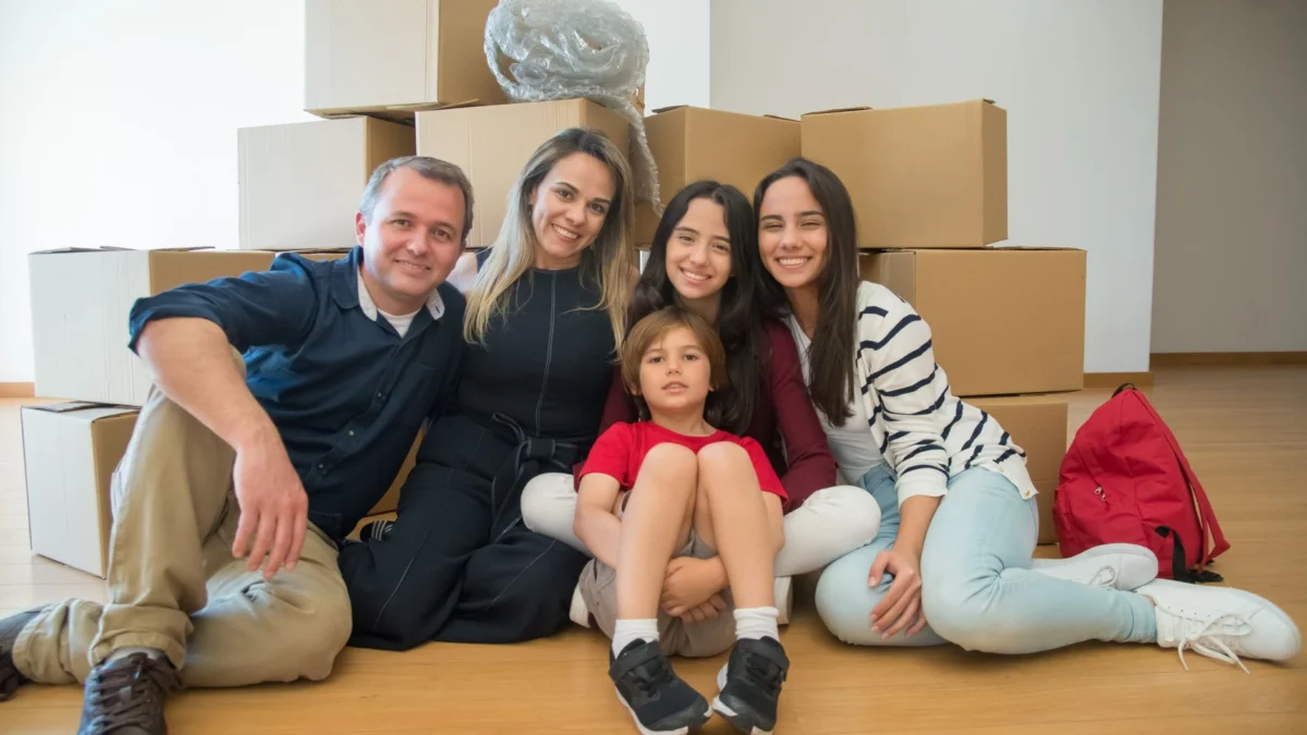Een vrolijke familie zit samen met verhuisdozen in hun nieuwe huis.