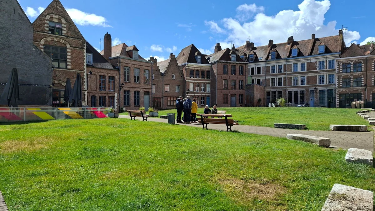 Toeristen genieten van een zonnige dag op een historisch plein met traditionele Franse architectuur in Lille, Frankrijk.