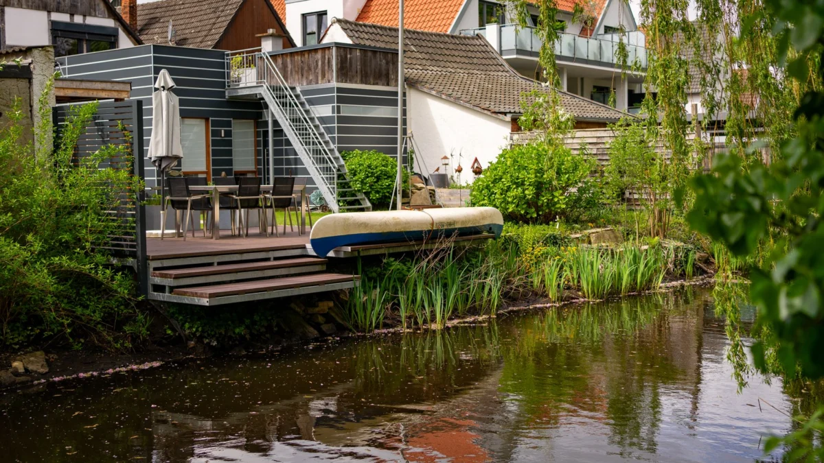 Pittoreske uitzicht op het kanaal met moderne huizen in Rietberg, Duitsland, met weelderig groen en een kano.