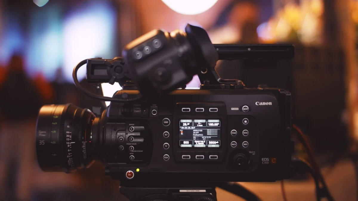 Close-up van een professionele videocamera in een studioomgeving, met lens en bedieningselementen.