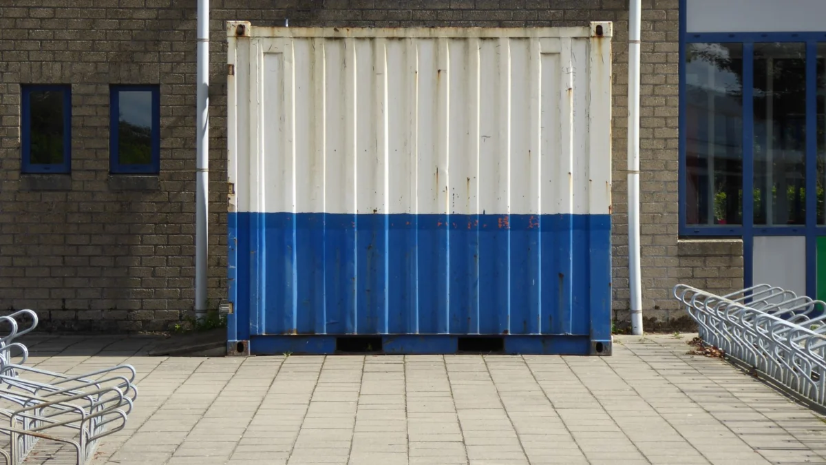 Een blauwe en witte container buiten geplaatst op een industriële locatie.