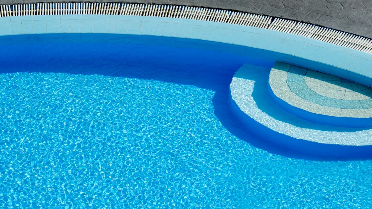 Van bovenaf vastgelegd zonovergoten zwembad, met helder blauw water en elegante lijnen.